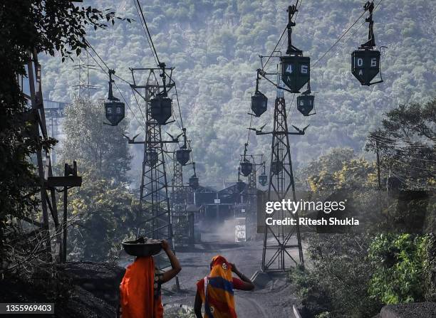Workers walk beneath a line of cable trolleys transporting coal from a mine to thermal power stations on November 22, 2021 in Sonbhadra, Uttar...