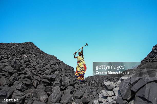 Workers break down coal at a coal yard near a mine on November 23, 2021 in Sonbhadra, Uttar Pradesh India. India is rapidly transitioning to...