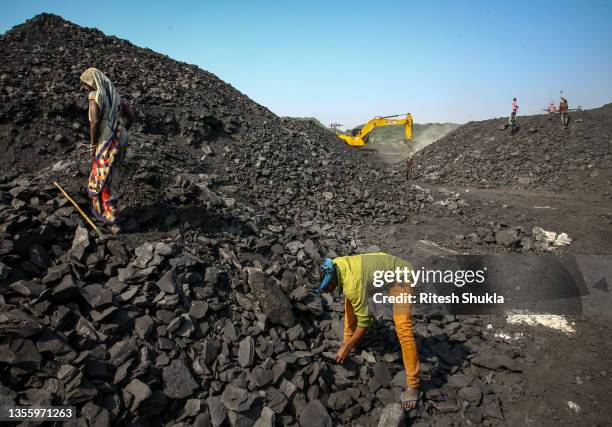 Workers break down coal at a coal yard near a mine on November 23, 2021 in Sonbhadra, Uttar Pradesh India. India is rapidly transitioning to...