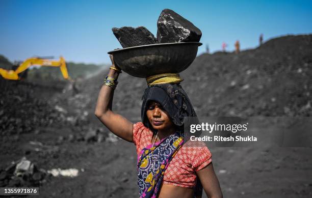 Workers carry coal at a coal yard near a mine on November 23, 2021 in Sonbhadra, Uttar Pradesh India. India is rapidly transitioning to renewables,...
