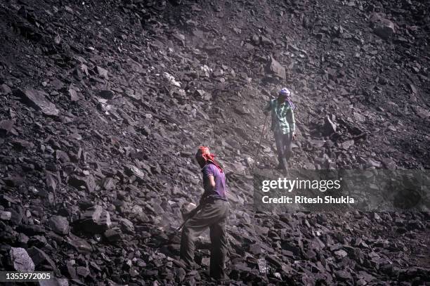 Workers break down coal at a coal yard near a mine on November 23, 2021 in Sonbhadra, Uttar Pradesh India. India is rapidly transitioning to...
