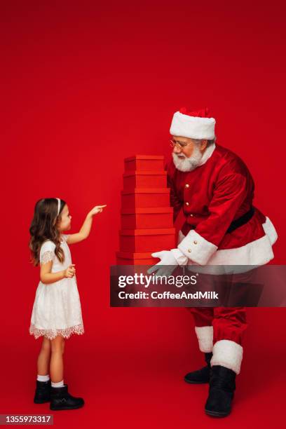 a cute little girl receiving a gift from santa claus - santa giving out presents stock pictures, royalty-free photos & images