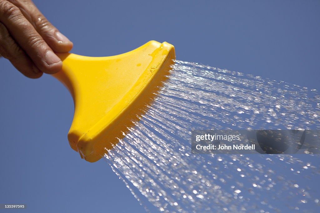 Yellow plastic hose nozzle with water shooting out