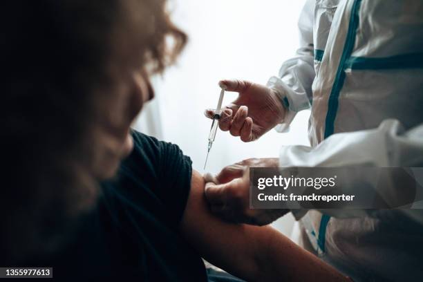doctor doing the covid 19 vaccine at home for omicron variant - injecting bildbanksfoton och bilder