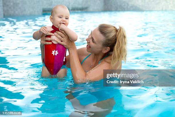 happy young mother swims and kisses  adorable baby in the pool or in the sea. - happy arab family on travel stockfoto's en -beelden