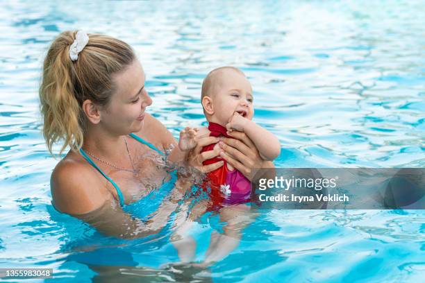 happy young mother swims and kisses  adorable baby in the pool or in the sea. - dubai spa stock-fotos und bilder