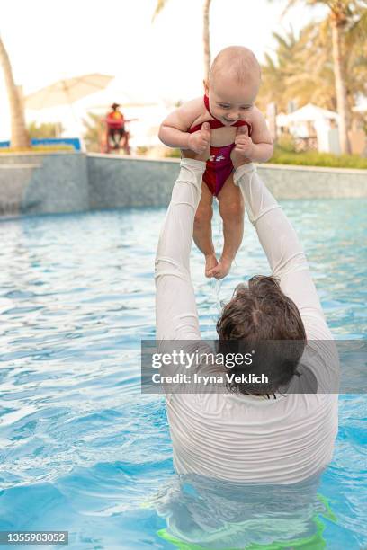 happy grandpa holding grandchild and  swims with  adorable baby in the pool or in the sea. - happy arab family on travel stockfoto's en -beelden