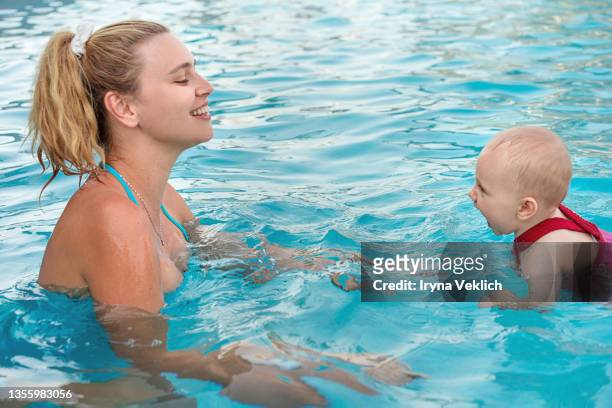 happy young mother swims and kisses  adorable baby in the pool or in the sea. - happy arab family on travel stockfoto's en -beelden