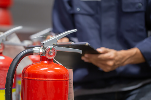 Engineer are checking and inspection a fire extinguishers tank in the fire control room for safety training and fire prevention.