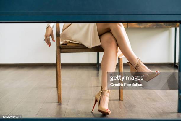 a woman sitting at the table - pernas cruzadas imagens e fotografias de stock