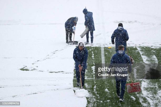 Groundsman attempt to clear snow from the pitch prior to the Premier League match between Burnley and Tottenham Hotspur at Turf Moor on November 28,...