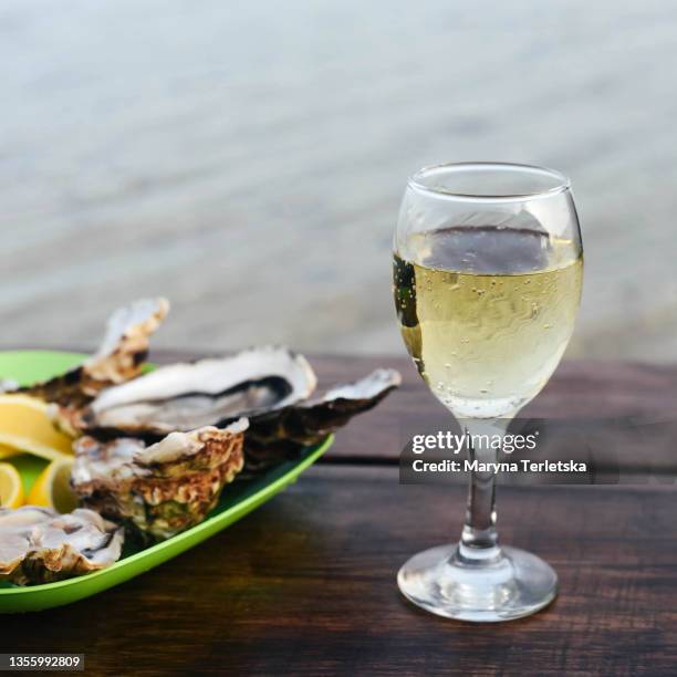 oysters with lemon in a green plate on a wooden table background. - beach bowl stock pictures, royalty-free photos & images