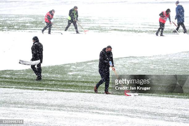 Groundsman attempt to clear snow from the pitch prior to the Premier League match between Burnley and Tottenham Hotspur at Turf Moor on November 28,...