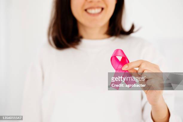 woman hand holding pink ribbon breast cancer awareness - cancer prevention stock pictures, royalty-free photos & images