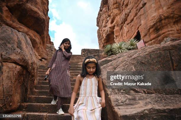 mother and daughter climbing down steps of an ancient hindu stone cave temple, badami, karnataka - indian mythology stock pictures, royalty-free photos & images