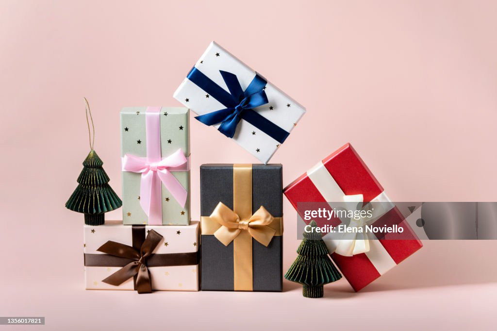 Festive christmas new year background colorful gift boxes and holiday decorations on pink background. New Year's present and Christmas present top view