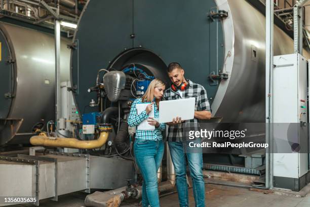 teamwork in the boiler room. young technicians are inspecting heating system in boiler room - district heating stock pictures, royalty-free photos & images