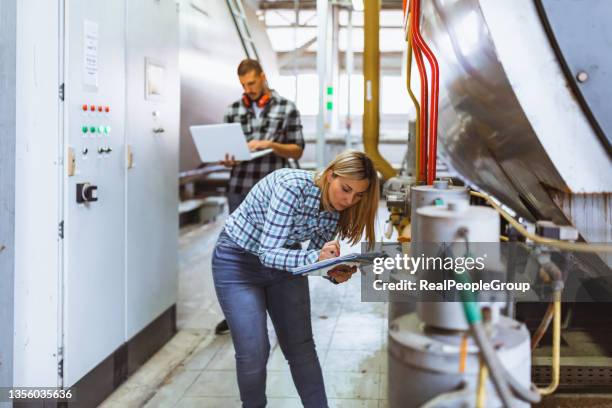 two engineers inspecting equipment of heating system in a boiler room - pipe women stock pictures, royalty-free photos & images
