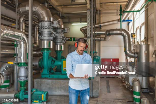 young technician is checking heating system in boiler room - man mid 20s warm stock pictures, royalty-free photos & images