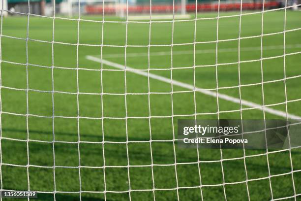 empty green grass soccer field against white goal net - soccer goal stock-fotos und bilder