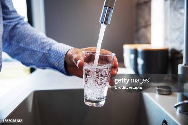 man pouring himself water - kraan stockfoto's en -beelden