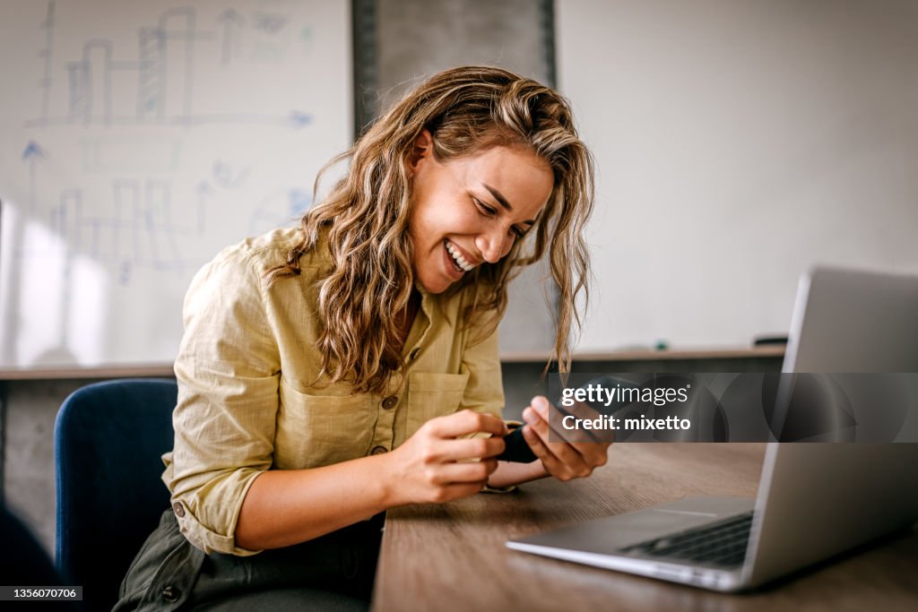 Women using smartphone and laptop laughing
