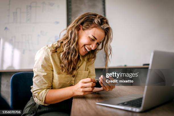 women using smartphone and laptop laughing - effortless imagens e fotografias de stock