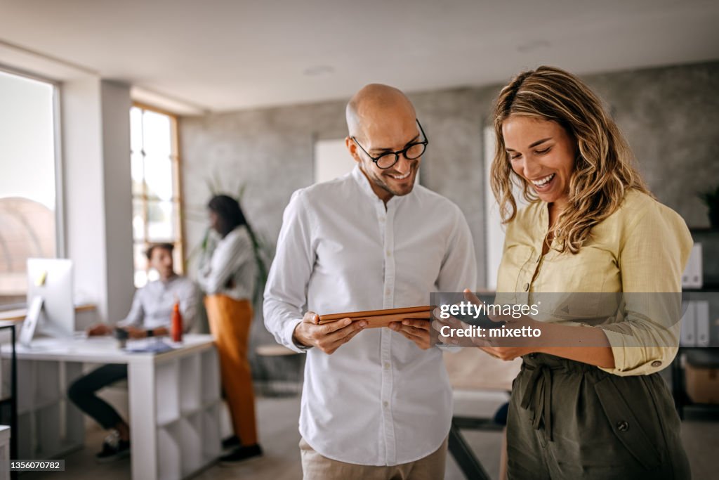 Businessman and businesswoman smiling looking at phone