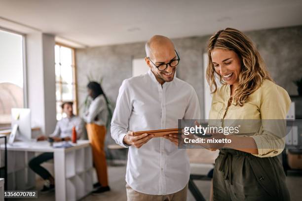 businessman and businesswoman smiling looking at phone - discussion imagens e fotografias de stock