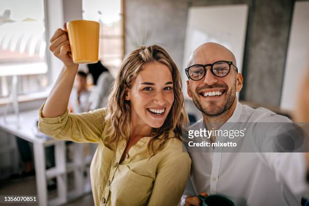 businesswoman taking selfie with colleague - fun at work stockfoto's en -beelden