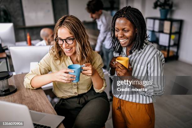 weibliche kollegen schauen auf laptop und lachen - company culture stock-fotos und bilder