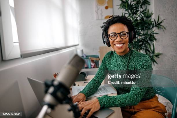 lächelnde junge frau, die am laptop arbeitet - podcast stock-fotos und bilder