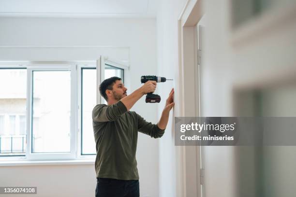 man drilling a hole in a wall - broca imagens e fotografias de stock
