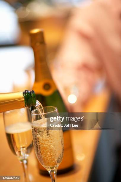 pouring a glass of champagne - champagner gläser mit flasche unscharfer hintergrund stock-fotos und bilder