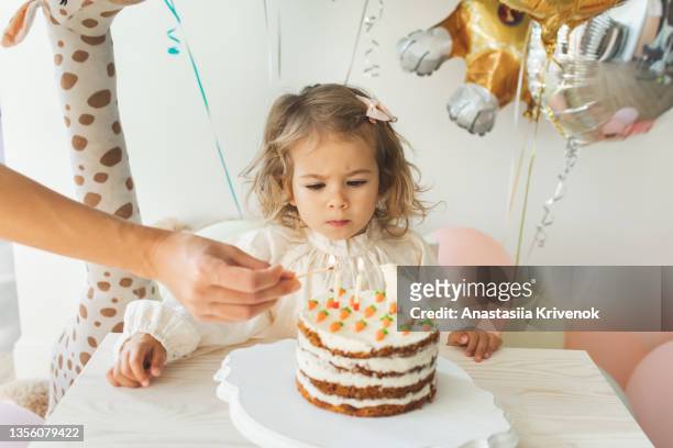 young girl blowing candles for celebreating her 2th years birthday. - 2 3 years stock-fotos und bilder