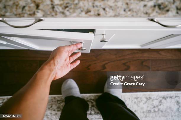 woman with hand on kitchen cabinet doorknob - manilla fotografías e imágenes de stock