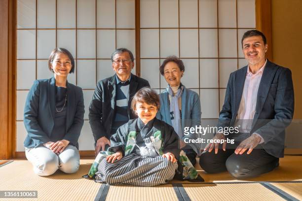 portrait of three generation multi-raced eurasian ethnicity family celebrating japanese traditional event called shichi go son. the boy dressed in japanese traditional clothing called hakama. - washitsu stock pictures, royalty-free photos & images