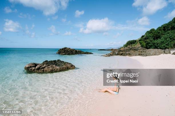 young girl sitting on tropical beach, okinawa, japan - okinawa islands stock pictures, royalty-free photos & images