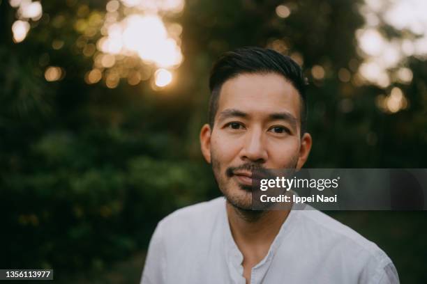 japanese man looking at camera at sunset, japan - in a japanese garden stock-fotos und bilder