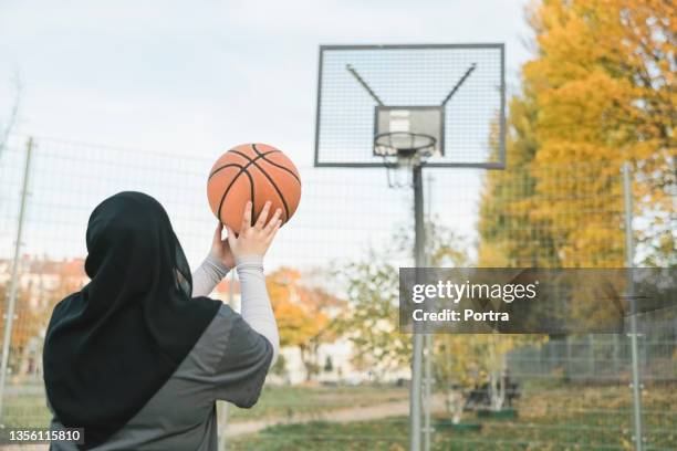 teenager-mädchen im hijab übt freiwurf auf basketballplatz - religiöse kleidung stock-fotos und bilder