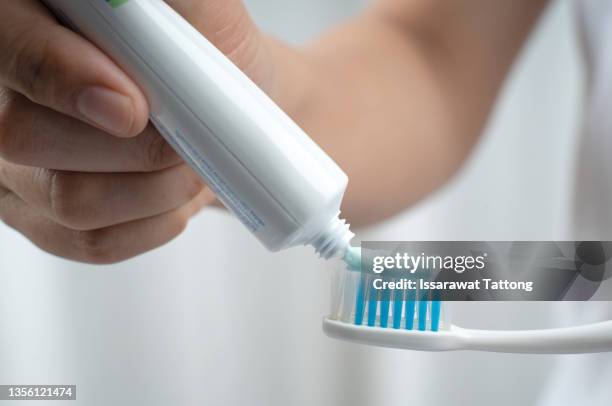 female squeezes toothpaste on the toothbrush - zahnpasta stock-fotos und bilder