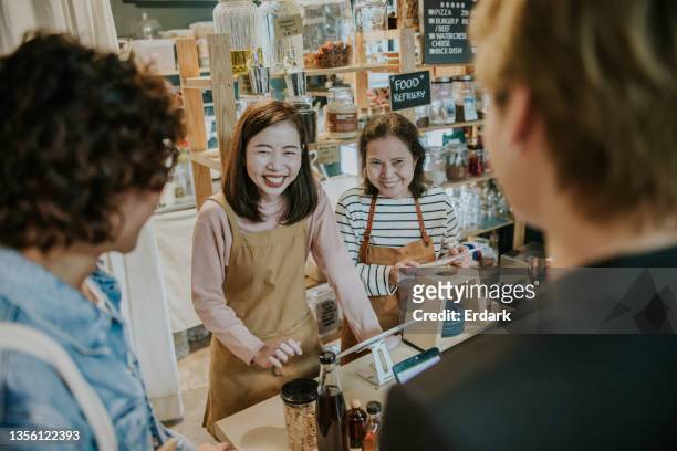 friendly asian cashiers with warm welcome to zerowaste store-stock photo - thai ethnicity stock pictures, royalty-free photos & images