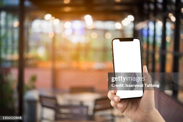 woman's hand shows mobile smartphone in vertical position and blurred background - social media profile stock pictures, royalty-free photos & images