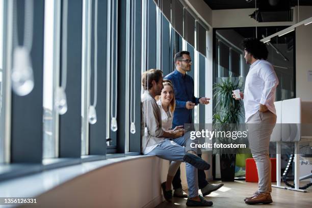 four business colleague hanging out and chatting during coffee break - wide shot of people stock pictures, royalty-free photos & images