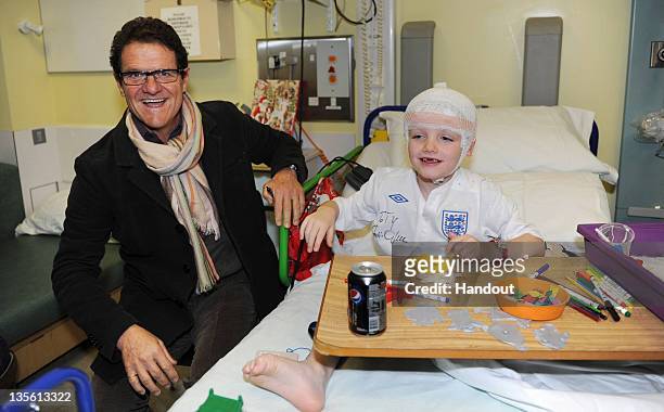 In this handout image provided by the FA, Manager Fabio Capello of England visits patient Tiarnan Smith on a visit to Great Ormond Street Hospital on...