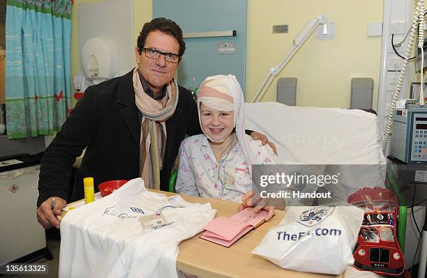 In this handout image provided by the FA, England manager Fabio Capello poses with patient Emily Ramsier on a visit to Great Ormond Street Hospital...