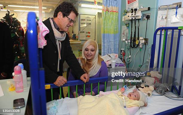 In this handout image provided by the FA, Manager Fabio Capello of England with patient Naima Essa on a visit to Great Ormond Street Hospital on...