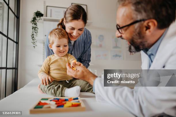 doctor and mother playing with child - doctor and baby stockfoto's en -beelden