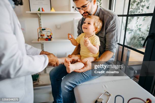 baby boy holding injection solution at medical clinic - doctor and baby stockfoto's en -beelden