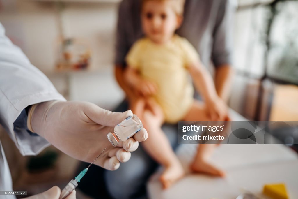 Doctor preparing vaccine for baby boy